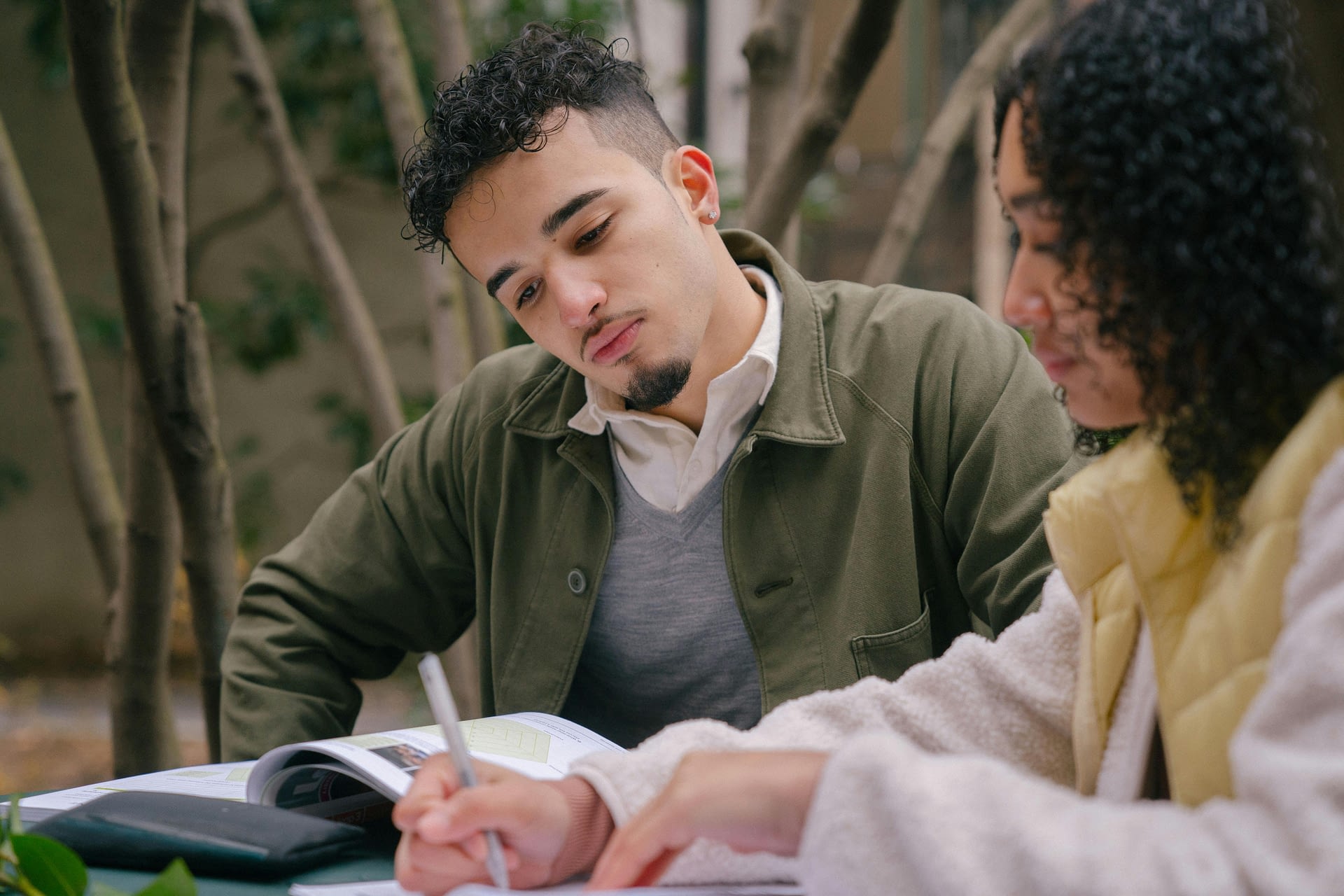 hidden power of curiosity -- a man and a woman studying on street at a table with books